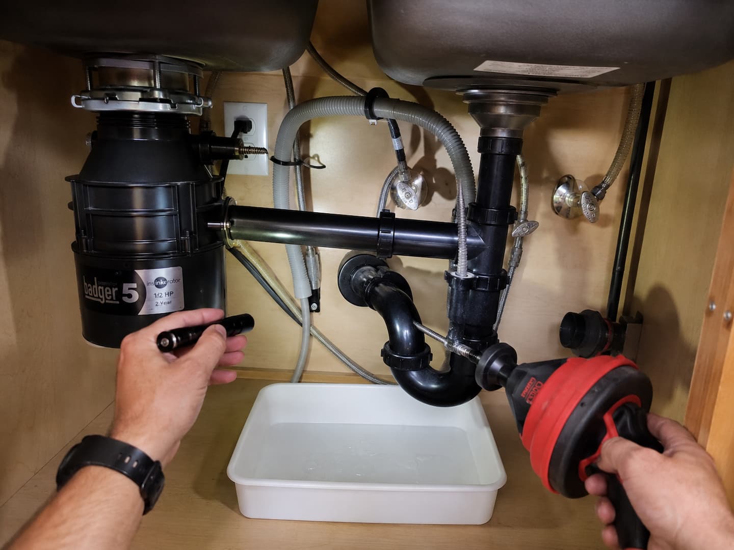 Plumber checking whether a garbage disposal issue is connected to the kitchen drain or dishwasher line