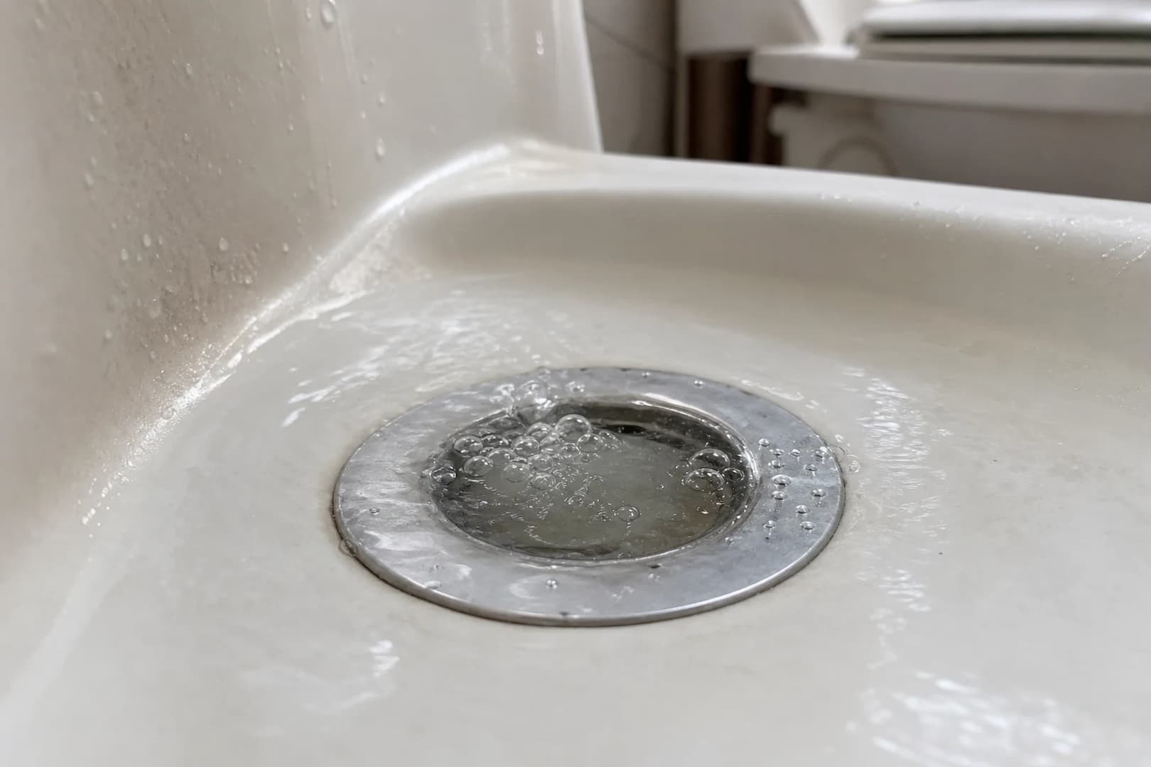 Close-up of bubbles and water movement at a bathtub drain after a toilet flush