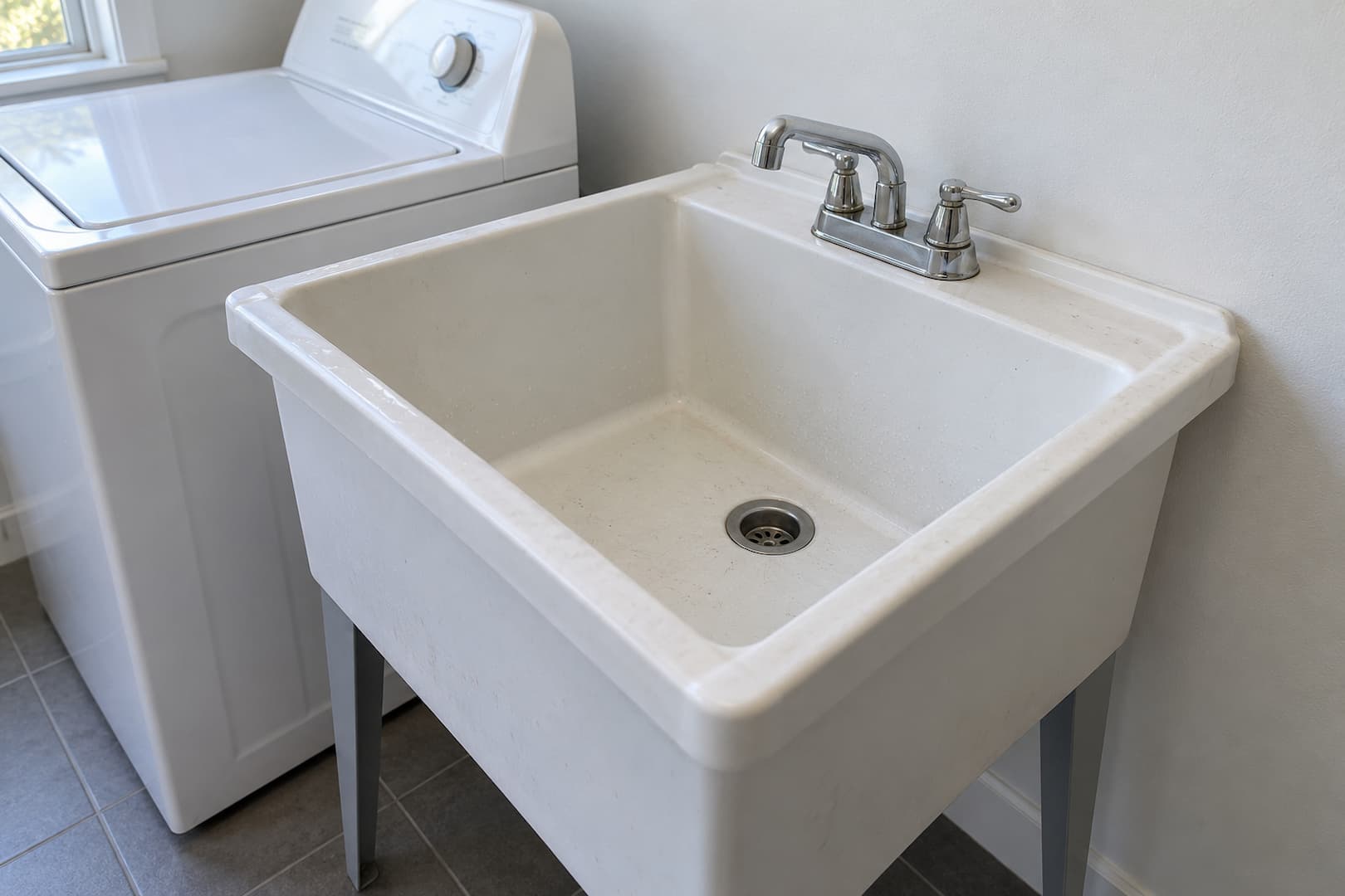 Laundry utility sink with a chrome faucet beside a washing machine