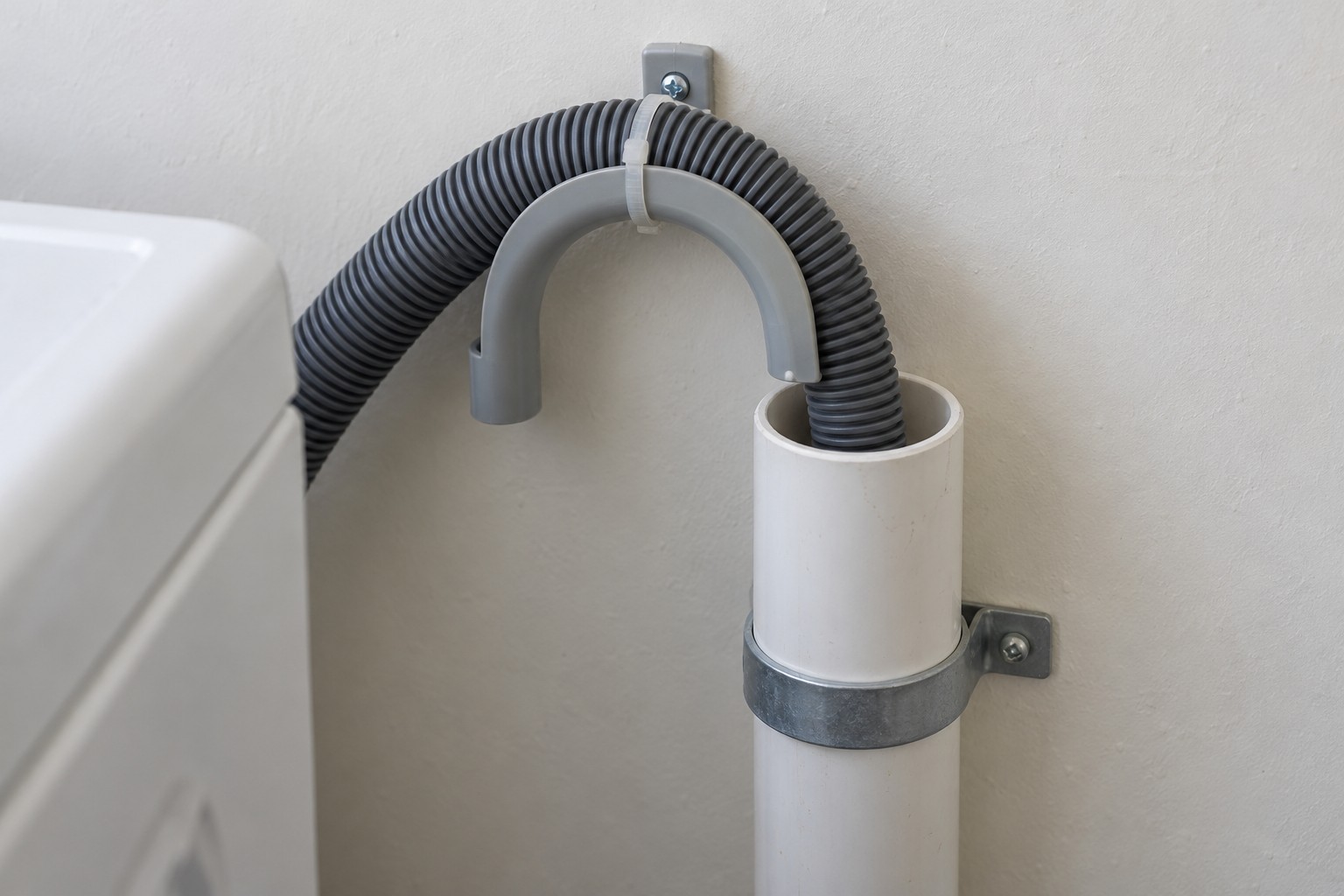Washing machine drain hose entering an open standpipe with visible space around the hose